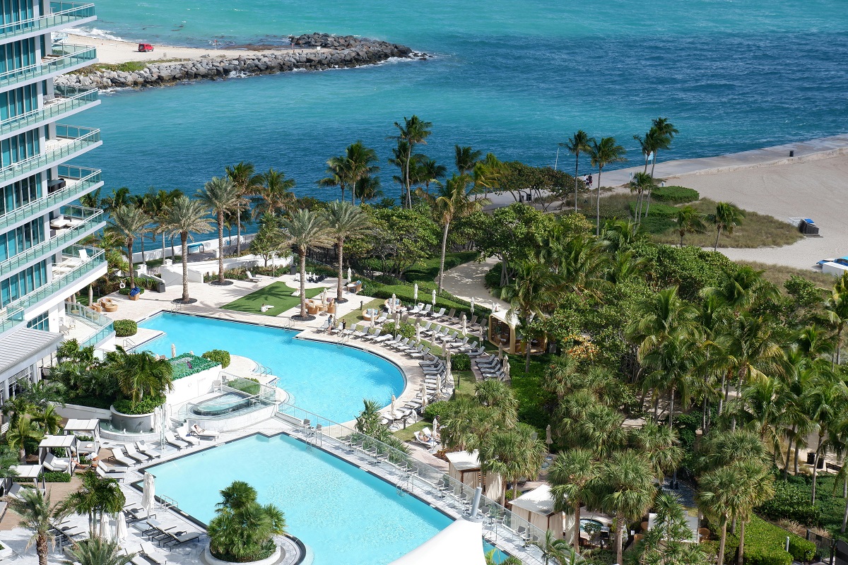 aerial view of a hotel in Miami near the beach, surrounded by palm trees and swimming pools